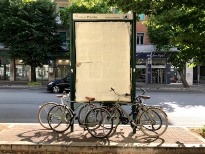 Nella foto ben quattro biciclette attaccate "indecorosamente" ai pali di un cartello pubblicitario: spazio occupato meno di 4 mq, contro 40 mq certi di 4 automobili. Nell’intorno immediato nessun stallo libero per bici. Poi altre foto di bici sul lungomare, con stalli bici saturi.